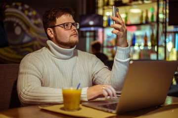 The serious young man working on laptop at cafe