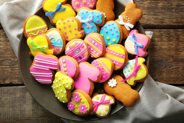 Plate with delicious Easter cookies and napkin on wooden table