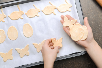 Woman putting raw Easter cookies on baking tray, closeup