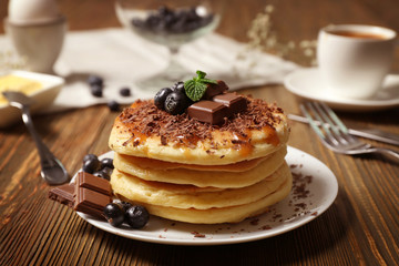 Stack of fresh pancakes with chocolate on wooden table