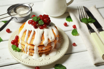 Stack of fresh pancakes with berries on wooden table