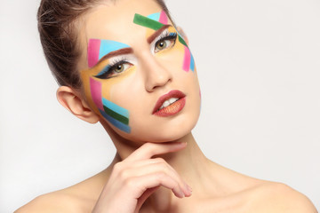 Face of beautiful young woman with creative make up on light background