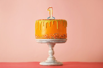 Birthday cake with one candle on pink background
