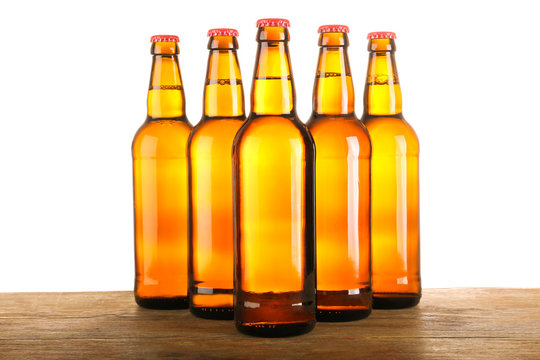 Beer bottles in a row on wooden table and white background
