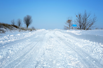 Obraz premium Country side empty road covered with snow on sunny day