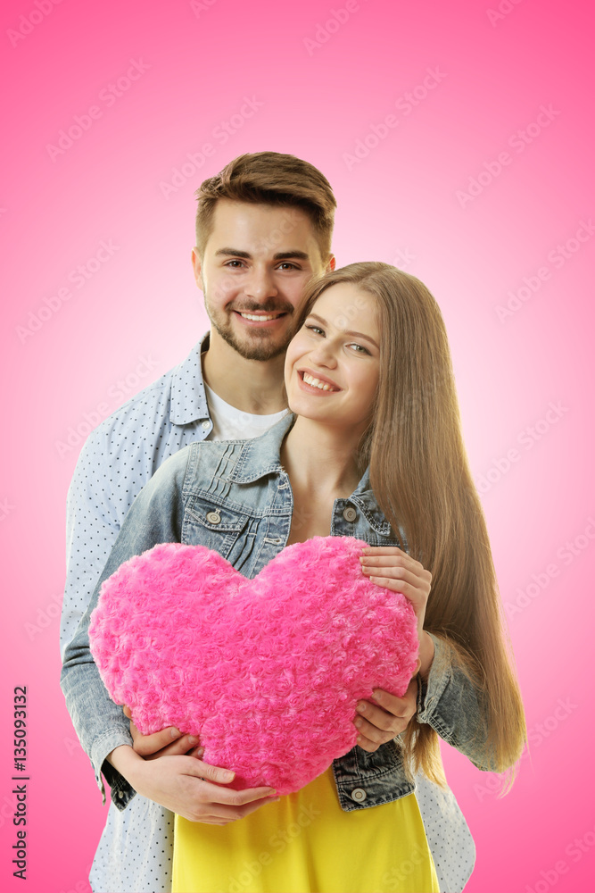 Wall mural Young couple with heart posing on color background