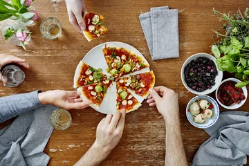 Foto op Aluminium three people sharing organic delicious pizza at dinner party © fneun