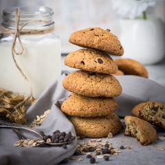 A stack of cookies with oatmeal and jar of milk