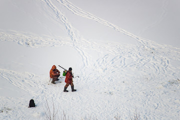 Two fishermen are on the ice in winter