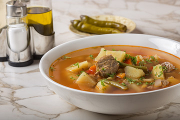 Bowl of vegetable beef soup and hot chilli peppers