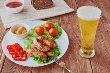 Grilled sausages with beer on a wooden background.