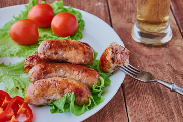 Grilled sausages with beer on a wooden background.