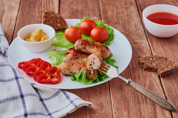 Grilled sausages with vegetables on a wooden background.