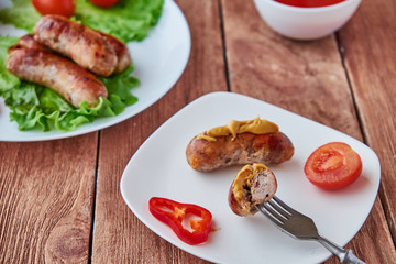 Grilled sausages with vegetables on a wooden background.