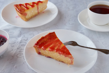 Slice of the New York cheesecake on a white plate on a wooden background .