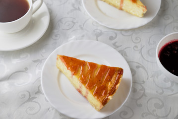 Slice of the New York cheesecake on a white plate on a wooden background .