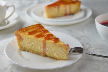 Slice of the New York cheesecake on a white plate on a wooden background 