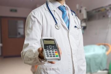 Doctor is holding payment terminal in hands. Paying for health care.