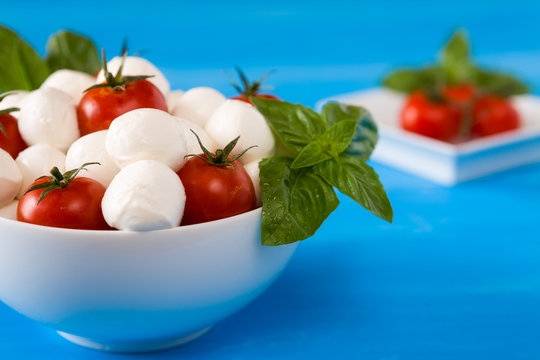 Closeup of mozzarella, cherry tomatoes and basil in a bowl
