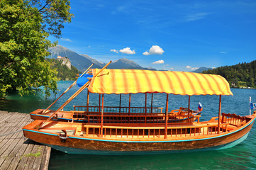 Fototapeta na wymiar Traditional Pletna boat on the lake. In the background is the famous old castle on the cliff.Bled lake Slovenia,Europe 