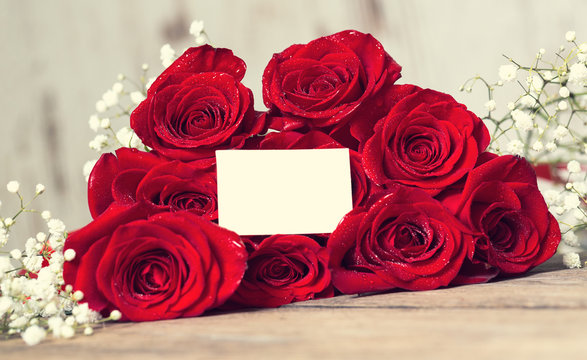 Bouquet of red roses on wooden table.