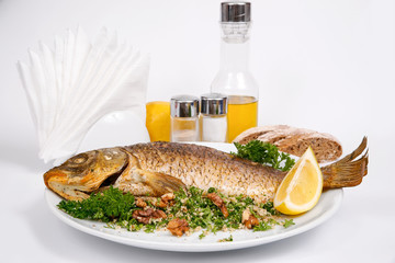 Carp stuffed with vegetables and raisins with greens and walnuts on a white plate