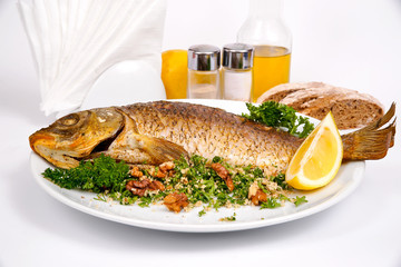 Carp stuffed with vegetables and raisins with greens and walnuts on a white plate