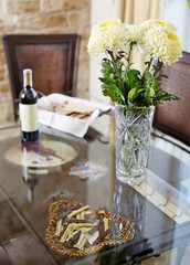 Beautiful vase with flowers and bottle of vine on glass diner ta