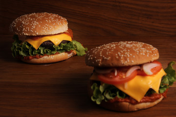 Homemade hamburger with double cheese, tomatoes, onions and grated carrots on a wooden table, unhealthy food. 