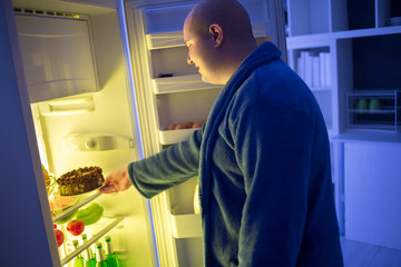 At night corpulent  guy take chocolate cake from refrigerator dangerous for obese