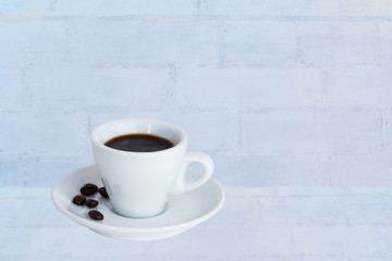 Cup of espresso coffee and coffee beans on white desk