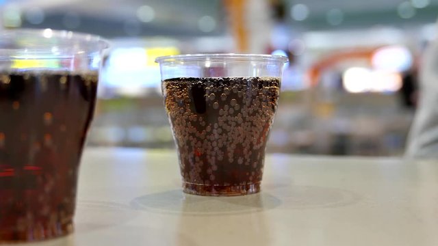 Two cups of coca cola on table inside shopping mall