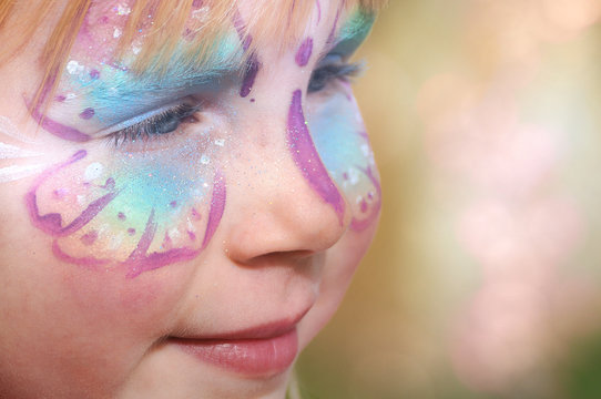 Mädchen freut sich über sein geschminktes Gesicht auf einem Freizeitpark