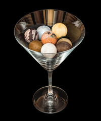 Semiprecious stones in the shape of a ball inside wineglass, isolated on the black background.