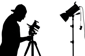 Silhouettes of photographer with camera on tripod, flash and light stand, isolated on the white background.