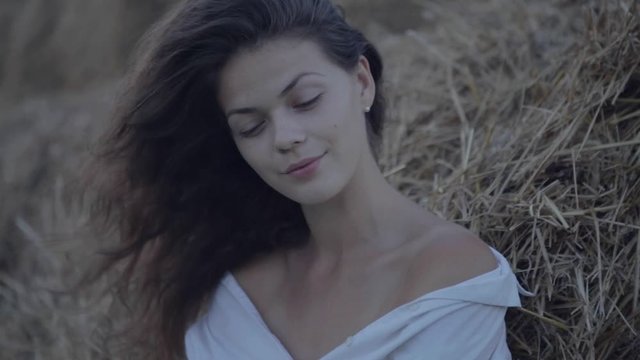Young pretty woman leaning hay. Cinemagraph