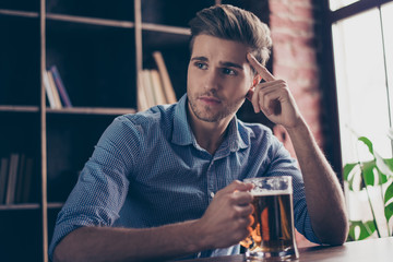 Minded man with glass of beer watching football at home