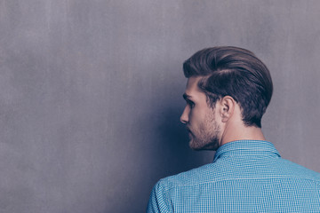 Back view of young modern brunet man on gray background