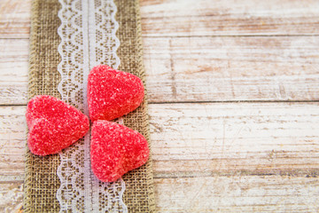 Valentine red candy hearts and natural lace ribbon on wooden board with room for copy
