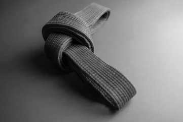 Papier Peint photo Arts martiaux Black judo belt tied in a knot isolated on black background