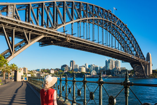 Woman in bright top and hat against Sydney Harbour Bridge on the
