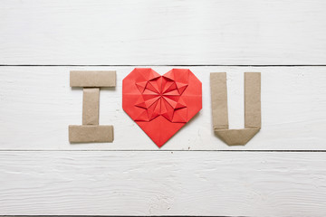 Red origami heart, craft paper folded letters I Love You (I, U) inscription on white painted rustic rural barn wood background. Nice Valentines day holiday greeting card, postcard.