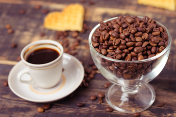 White coffee cup and coffee beans on old wooden background.
