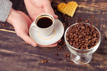 White coffee cup and coffee beans on old wooden background.