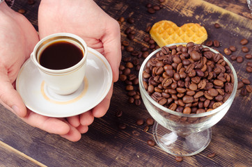 White coffee cup and coffee beans on old wooden background.