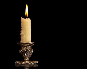 burning old candle vintage Silver bronze candlestick. Isolated Black Background.