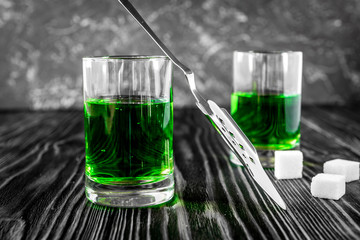 absinthe with sugar cubes and spoon on wooden background