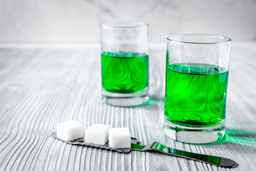 absinthe with sugar cubes and spoon on wooden background