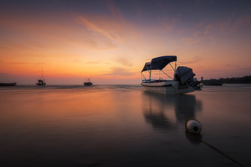 Fototapeta na wymiar Silhouette of travel boat with water reflection in beautiful sunrise at Rayong beach, Thailand