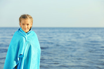 Cute girl wrapped in towel on beach